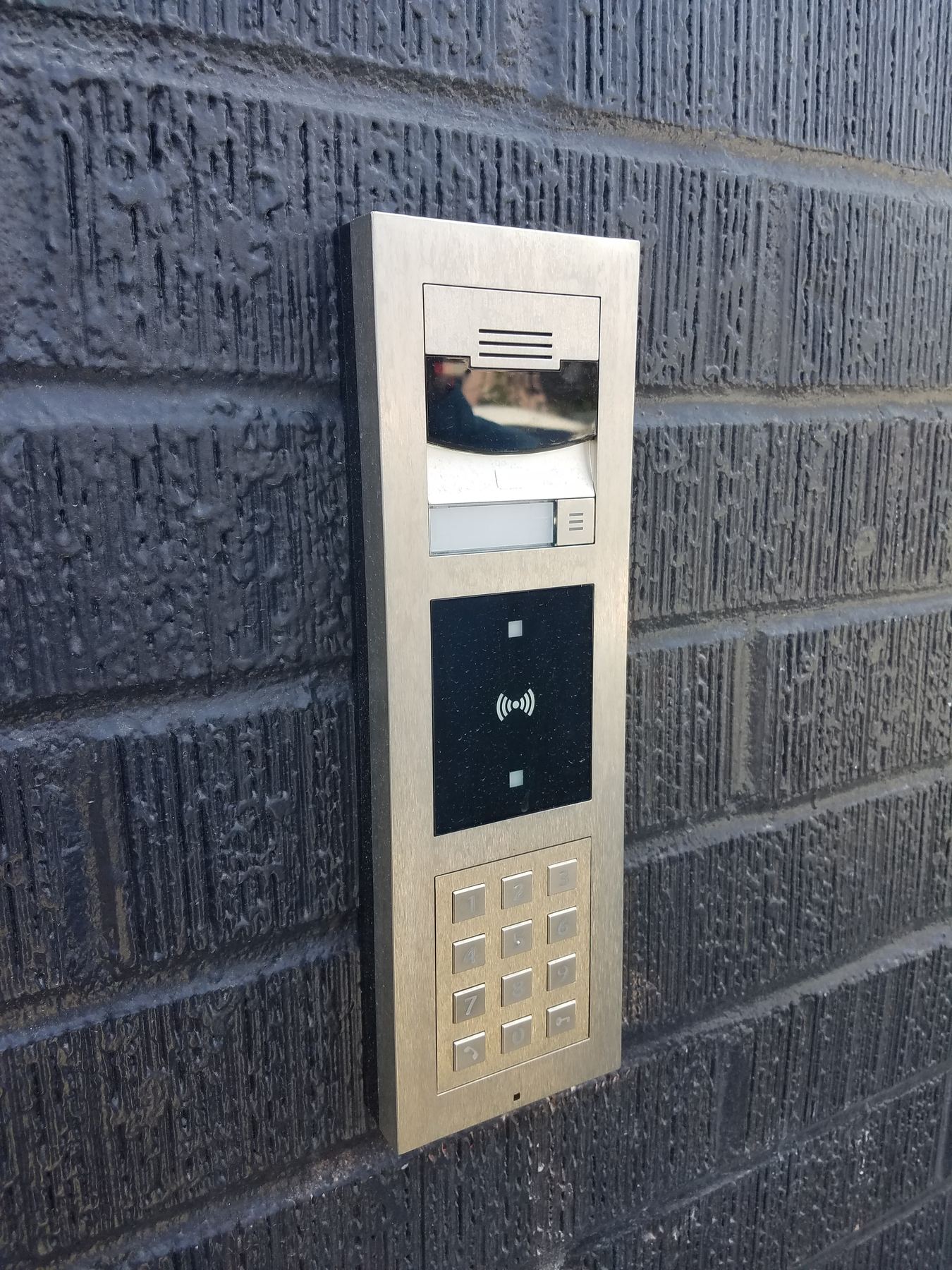 Stainless video door station with keypad and card reader on a brick wall