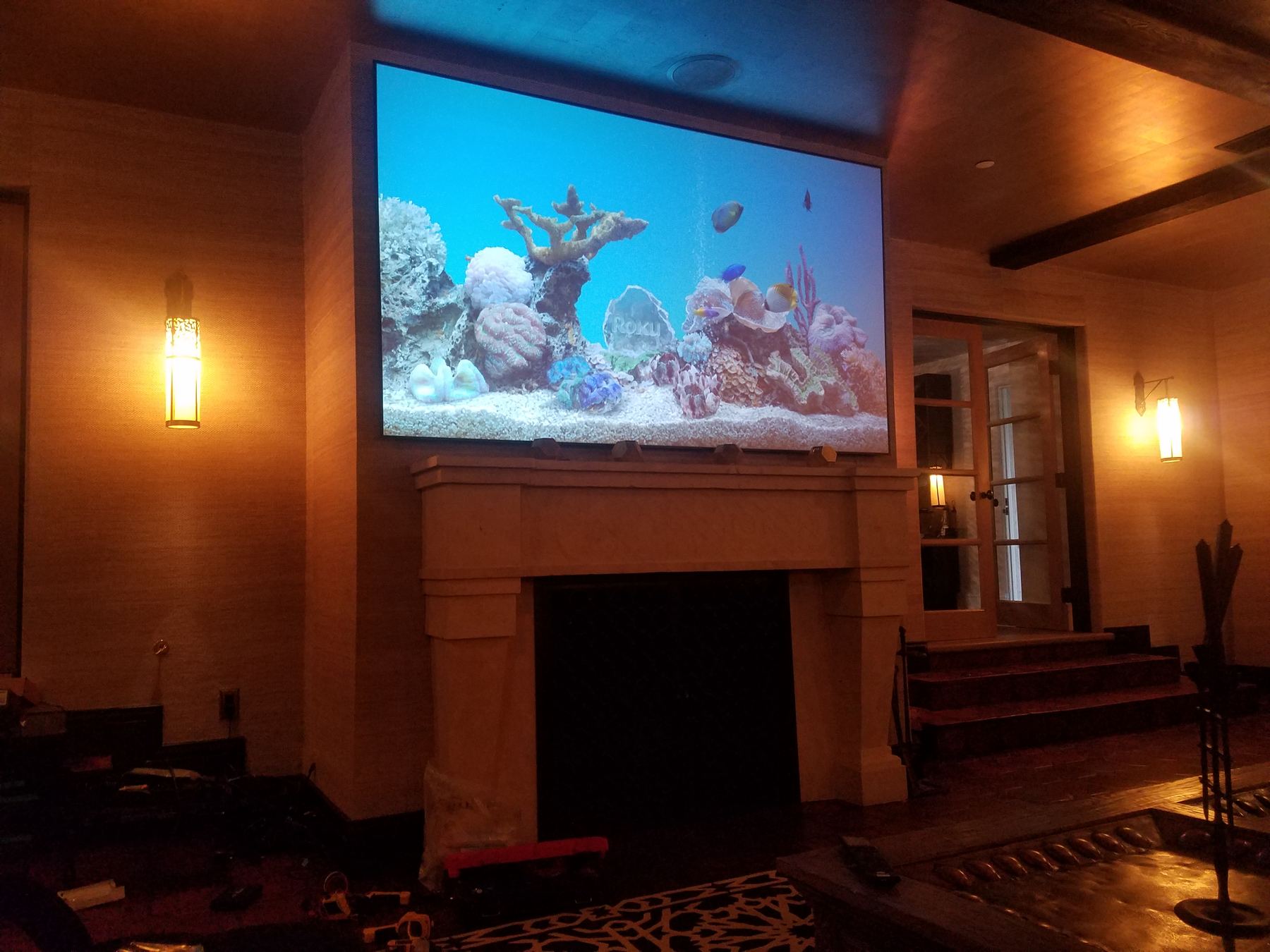 Projection screen over a fireplace in a wood-paneled living room