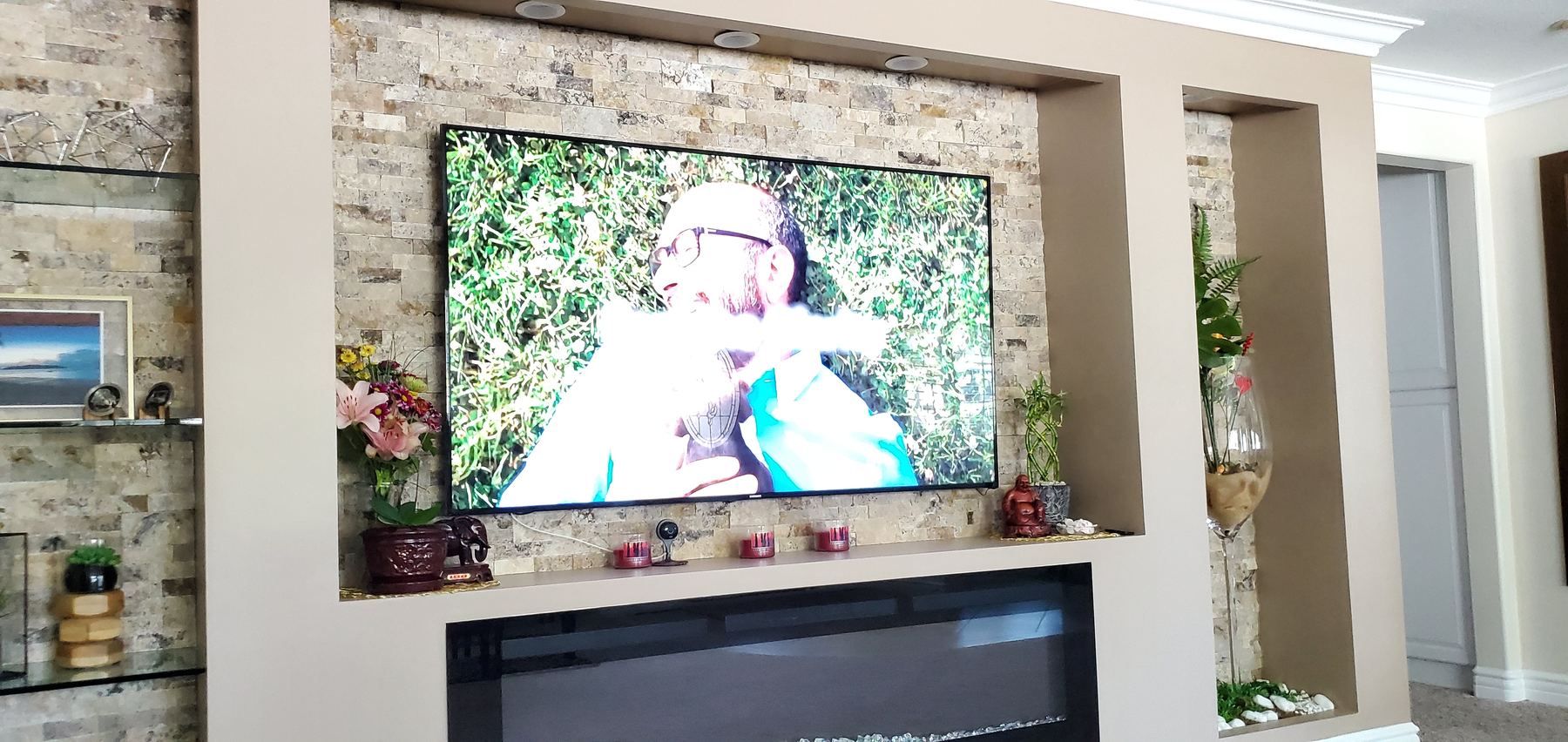 TV recessed into a stacked-stone wall above a fireplace