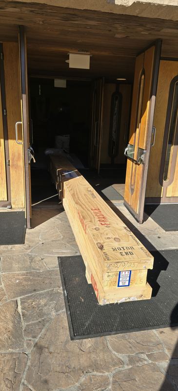 Crated 300-inch motorized projector screen marked motor end, delivered through the doors of a church for installation