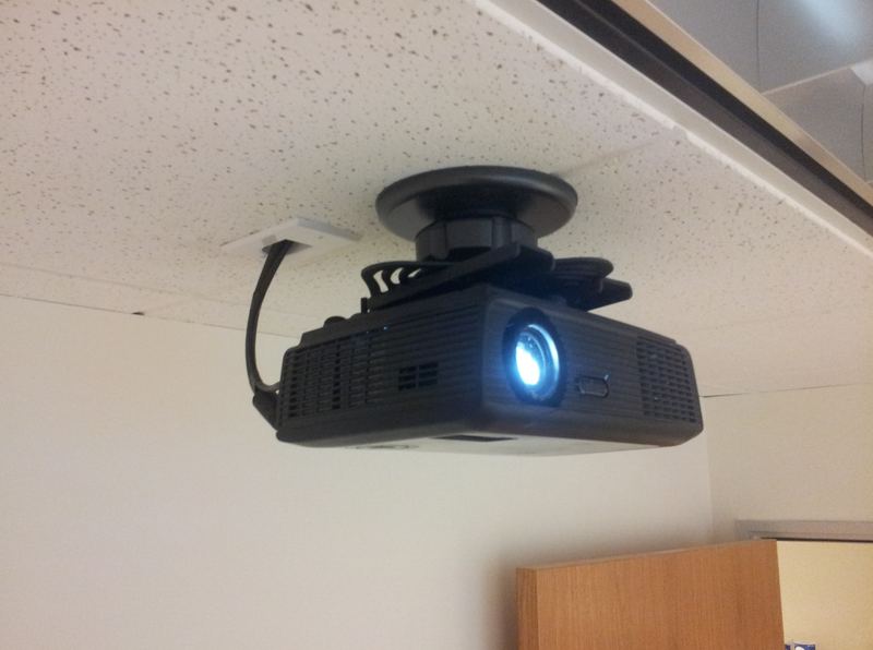 Business projector on a low-profile ceiling mount with cabling routed through a ceiling plate in an office